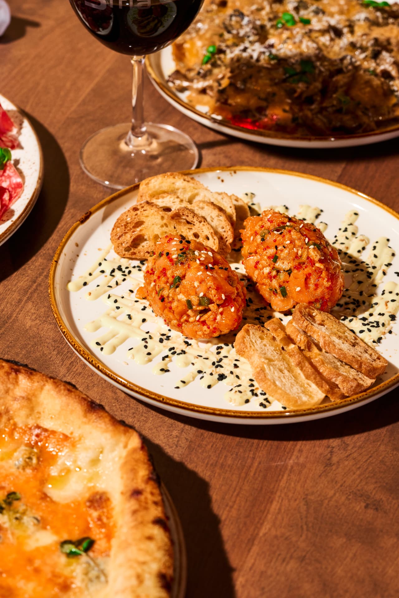 Table spread with salmon tartare, pizza and red wine at Industria